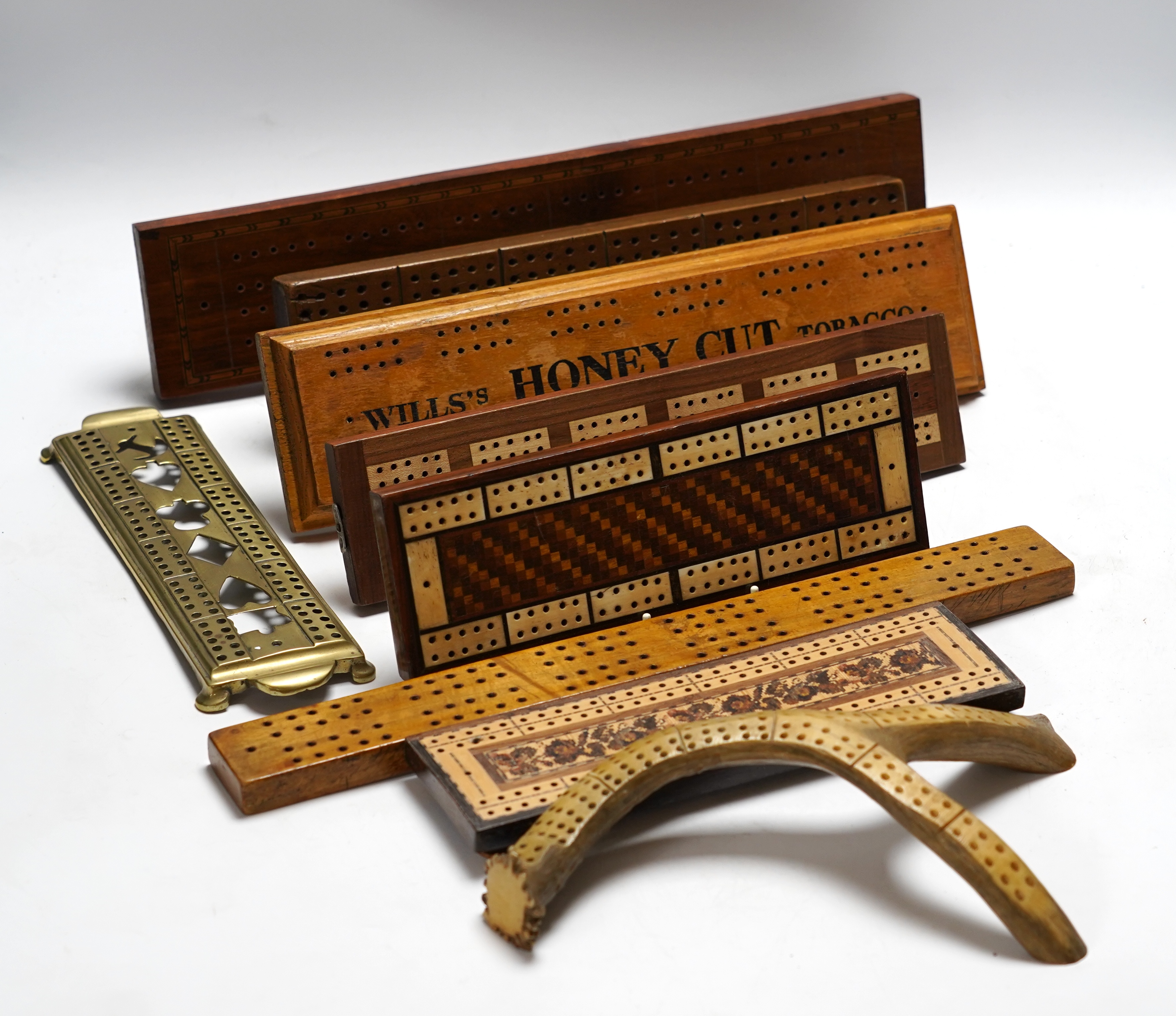 Nine cribbage boards including a horn example, 'Wills Tobacco' advertising and bone and marquetry examples, largest 42cm in length